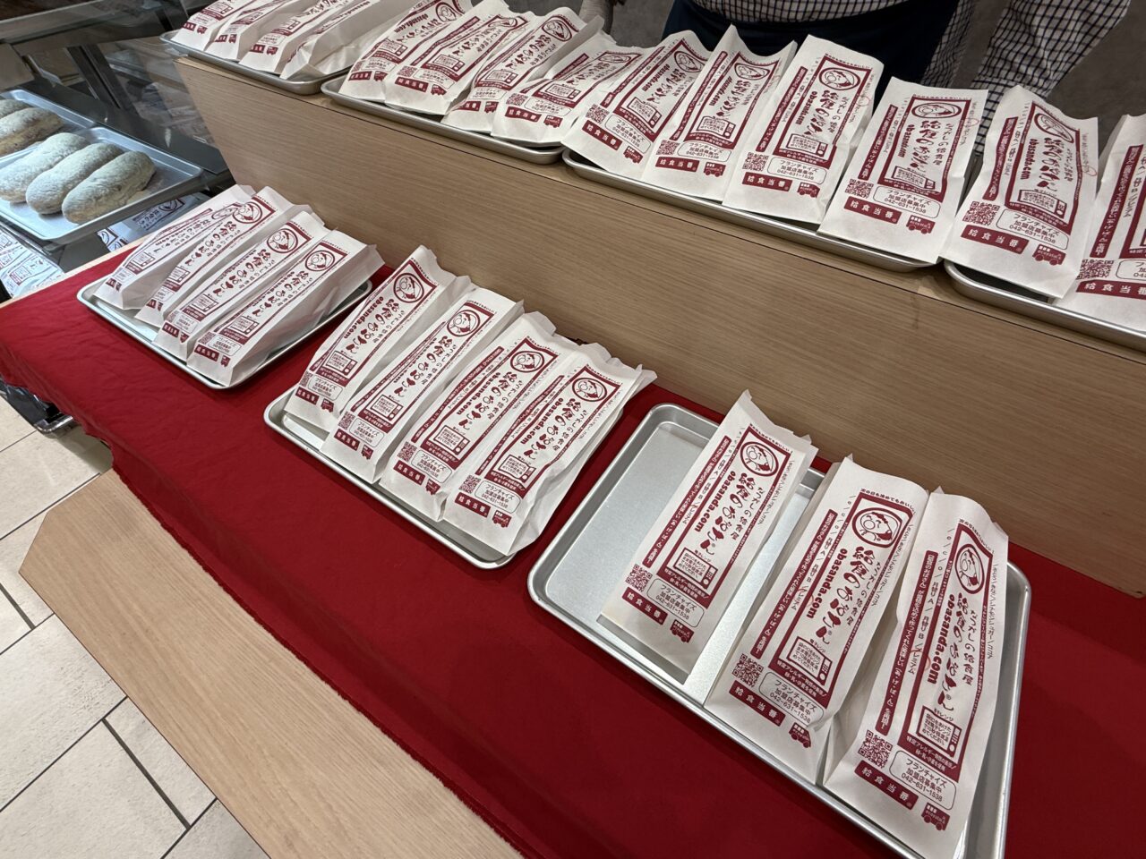 赤いテーブルクロスの上に並ぶあげぱん商品パッケージ