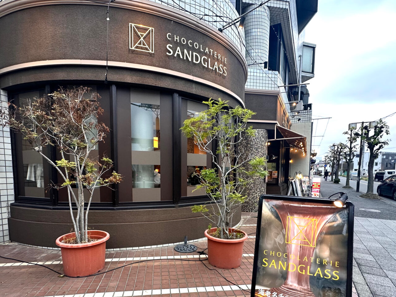海老名市中央にあるショコラトリーサンドグラス本店の外観。ブラウンカラーの建物と店頭看板