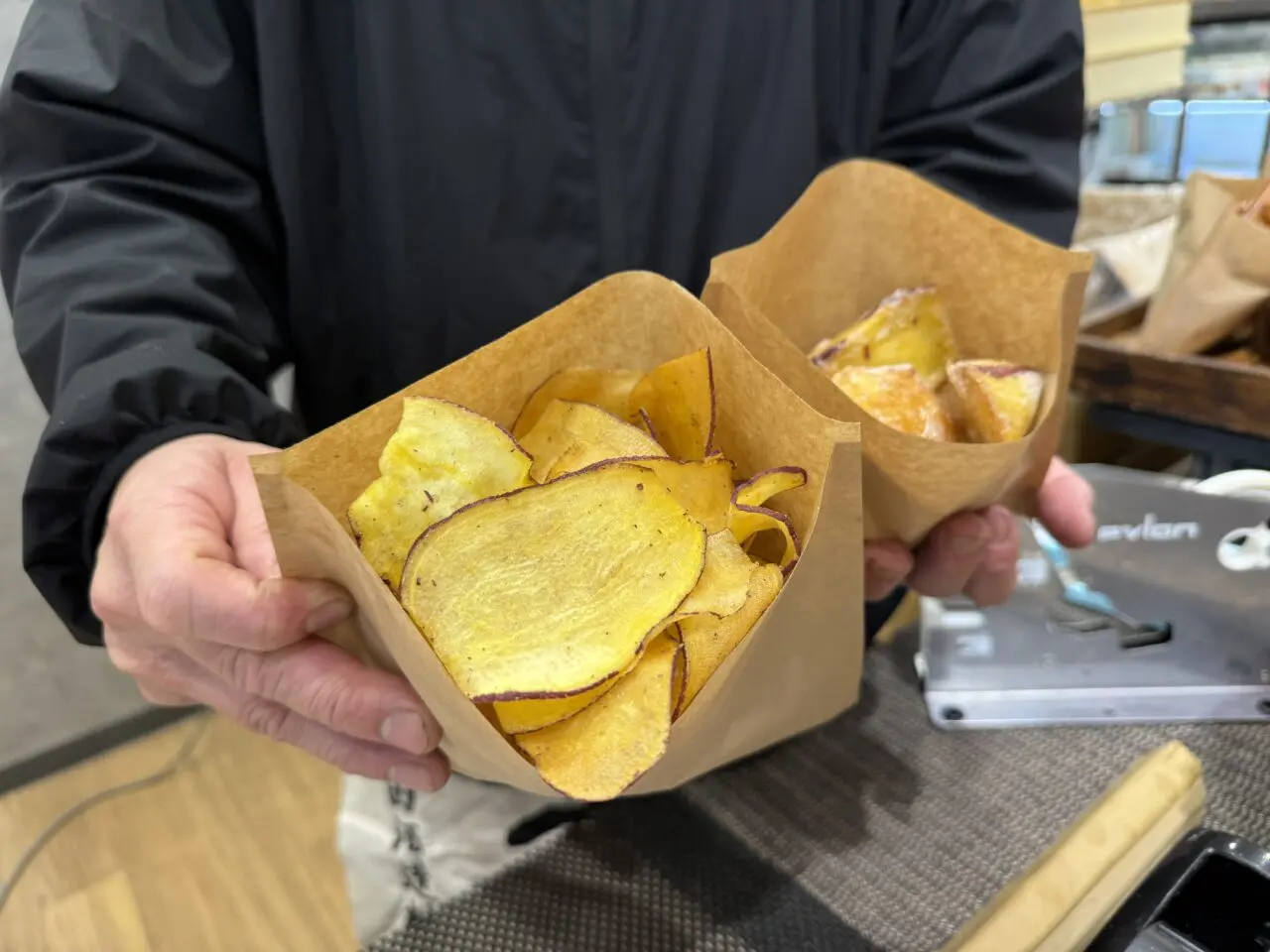 紙袋入りの芋チップスを持つ手元