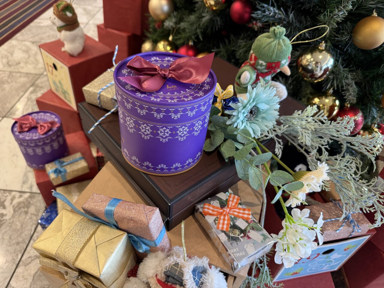 紫色のギフト缶やリボン付きプレゼントが並ぶクリスマスディスプレイ