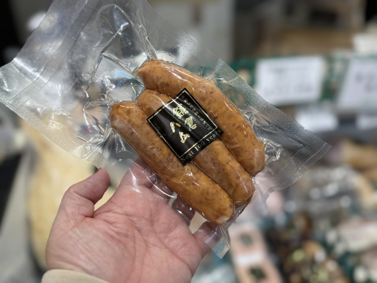 真空パック入りのLYB豚ソーセージを手に持った様子