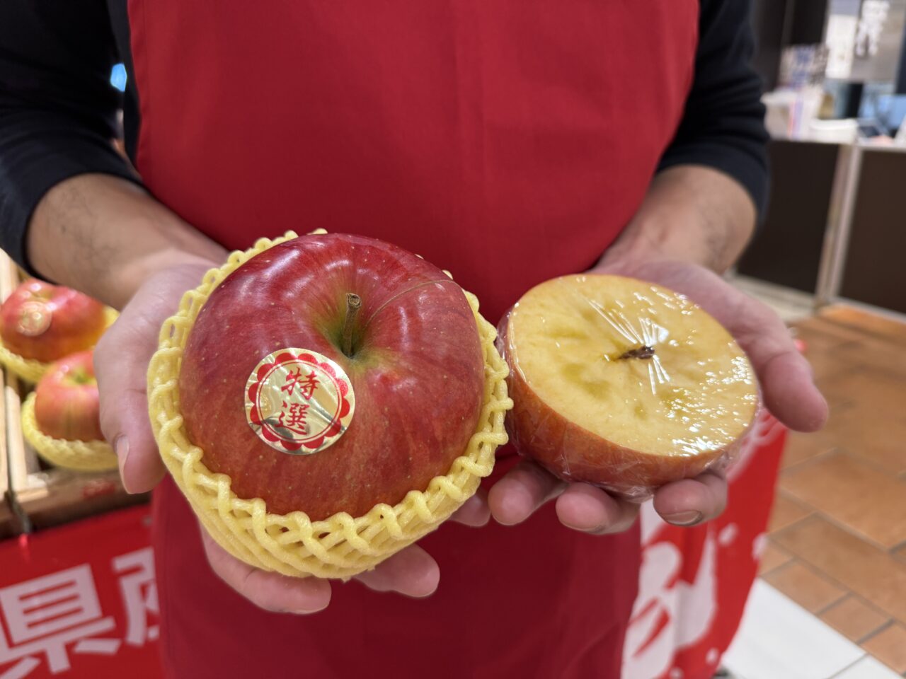 坂本健商店のスタッフが手に持つ特選りんごと蜜入りの断面。